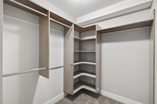 Large primary bedroom walk-in closet with custom shelving