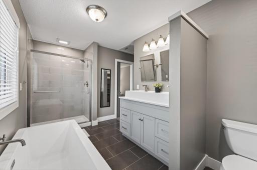 Stunning primary bathroom with tile floors, walk-in shower and soaking tub.