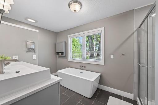 Stunning primary bathroom with tile floors, walk-in shower, and soaking tub.