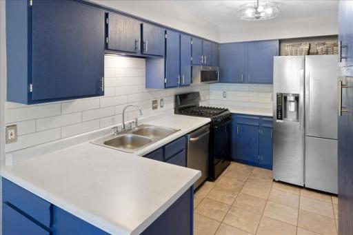 Stylish kitchen features tiled backsplash and stainless steel appliances (with gas range).
