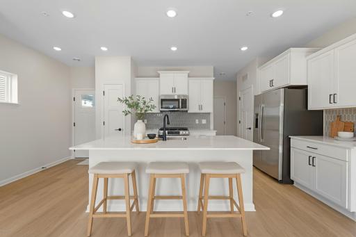 Kitchen features white cabinets with gold hardware and taupe backsplash with all appliances included - for illustrative purposes only