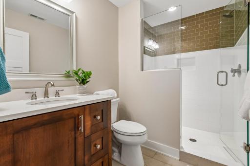 3/4th tiled bath with custom vanity, tile penny round flower shower, milk glass surround tile with clear glass shower door.