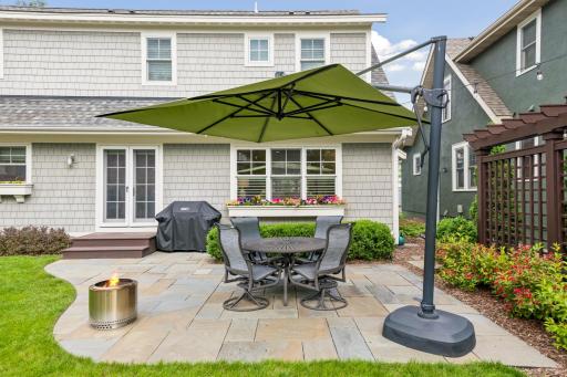 Back slate stone patio area to grill, entertain and be outdoors. Yard is professionally landscaped with sprinkler system and drips to window boxes for ease of watering.