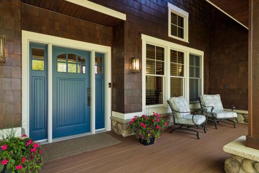Charming front two-story covered porch with new TimerTech decking (2025), freshly stained cedar shake siding (2025), stone accents, copper gutters & a stamped concrete walkway & concrete driveway border.