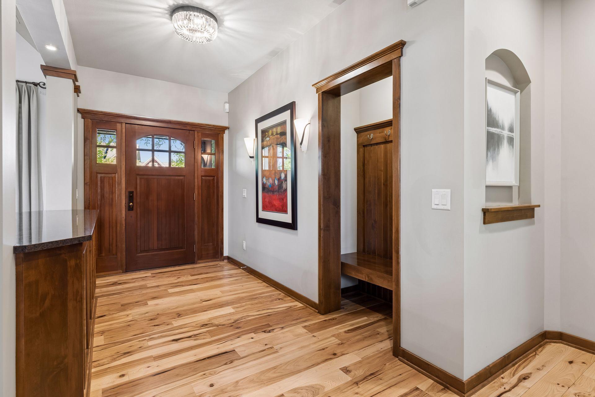 Spacious foyer with built-in coat nook with bench, gorgeous hickory hardwood floors, and a new light fixture.