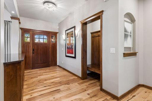 Spacious foyer with built-in coat nook with bench, gorgeous hickory hardwood floors, and a new light fixture.