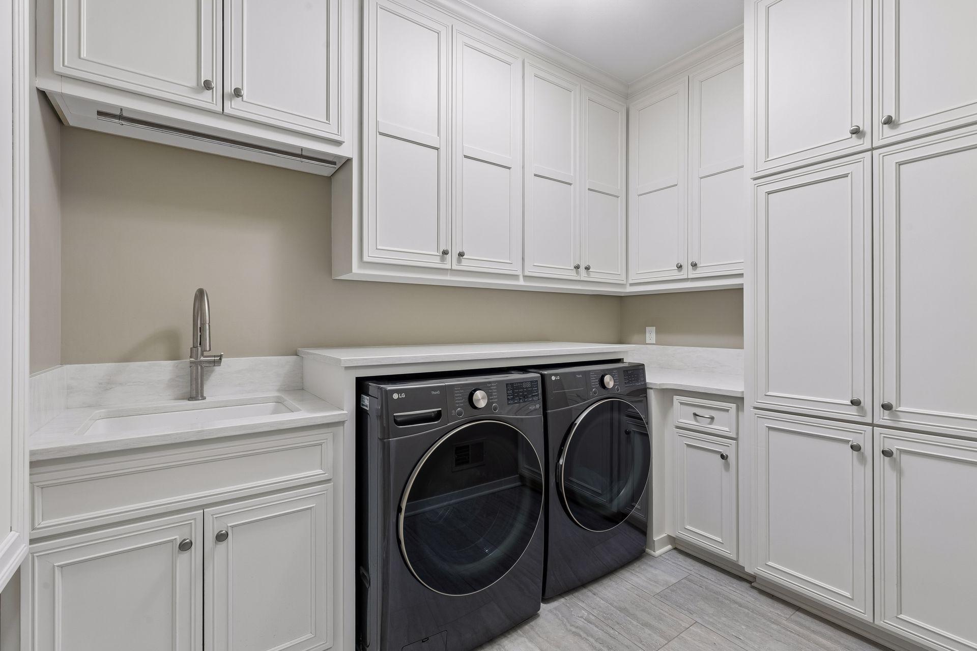 Laundry day won't be a chore in this laundry room. It features abundant storage cabinets, ceramic tile floors, front-load LG ThinQ washer & gas dryer w/folding counter, an extra-deep utility sink, built-in iron board & genius pull-out drying racks.