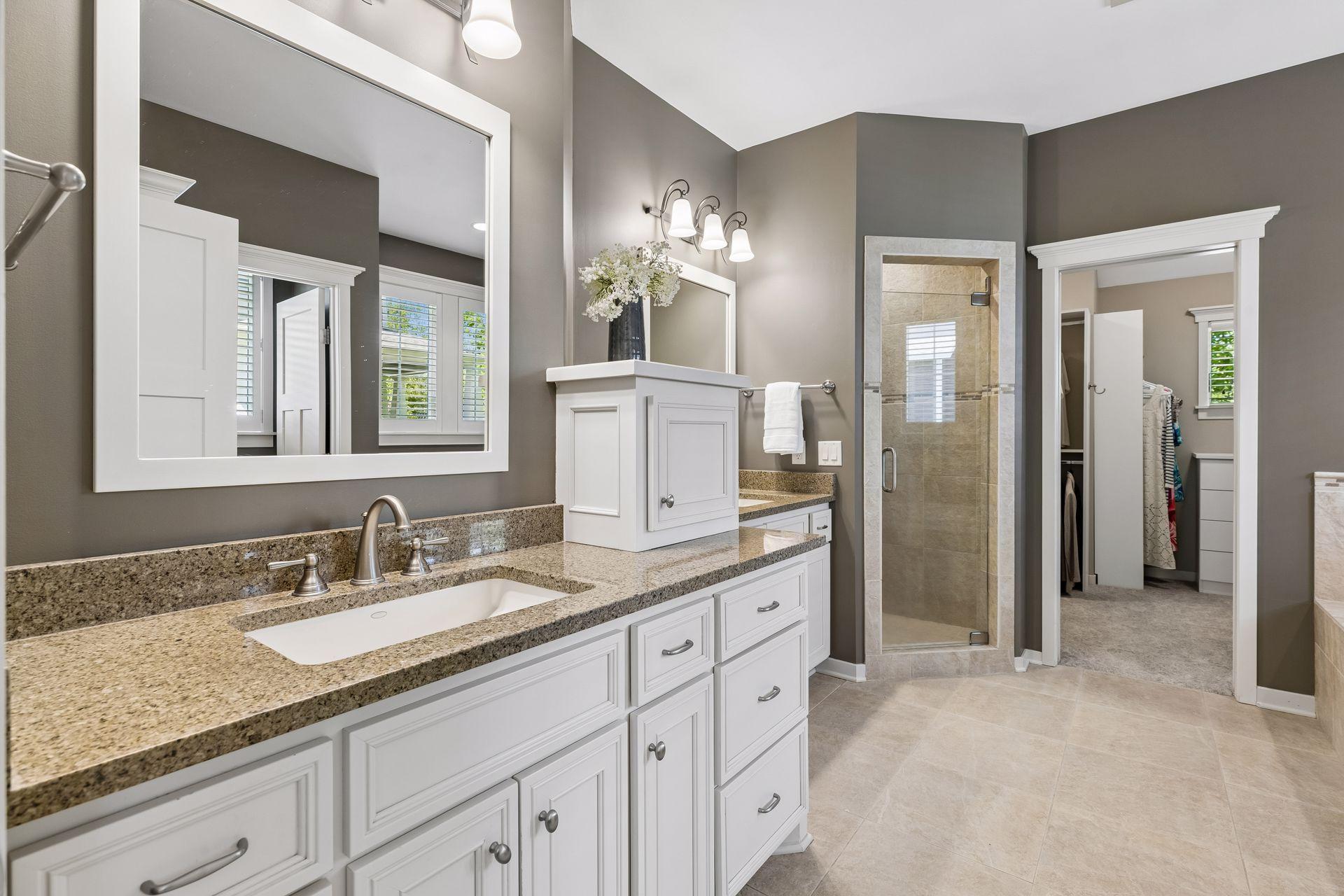 The spa-like private primary full bathroom features comfort-height granite vanity w/storage, heated ceramic tile floors, double sinks, double linen closet, separate water closet w/window, soaking tub w/ceramic tile surround & a walk-in shower.