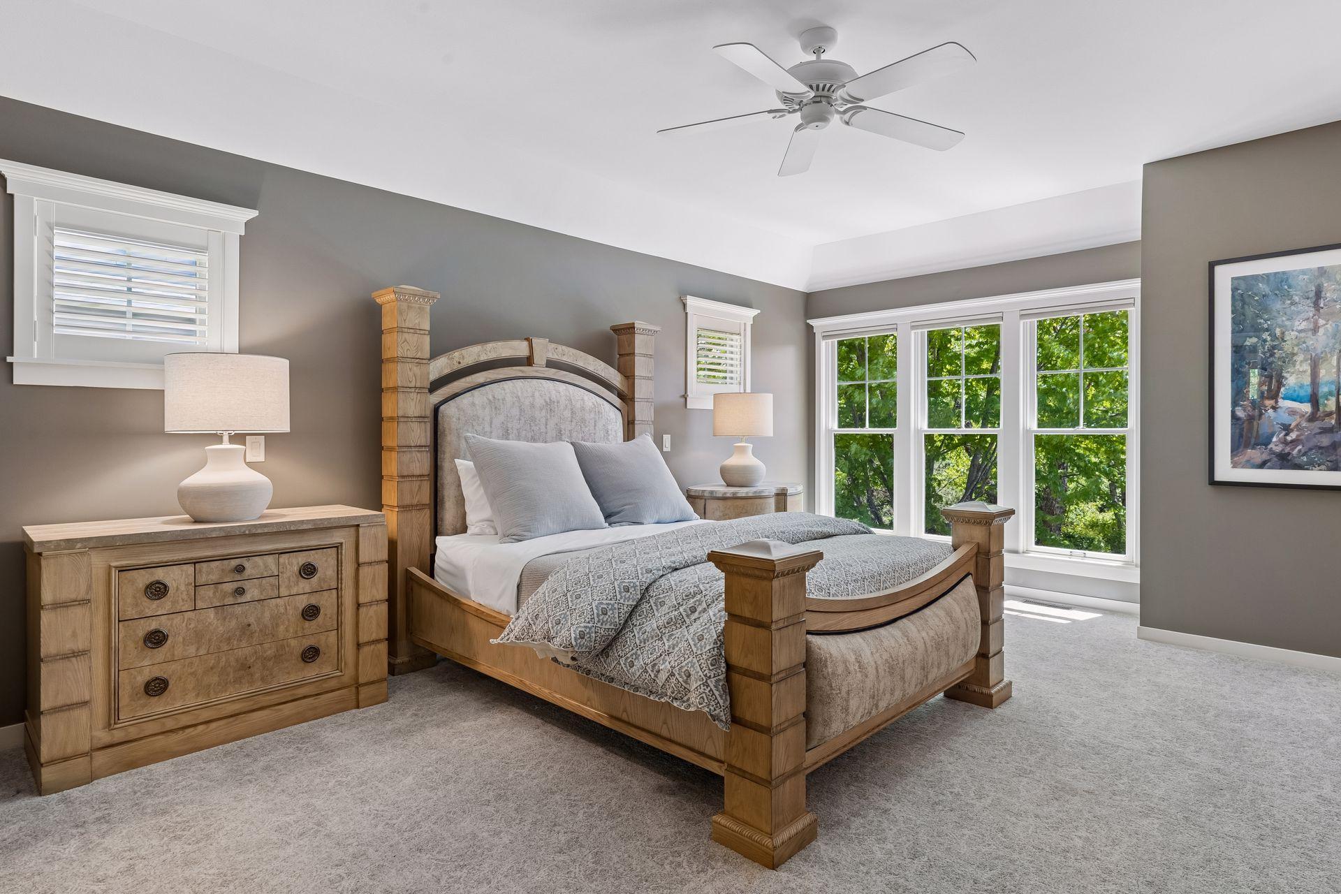 The primary bedroom suite is located on the main level. It features floor-to-ceiling windows overlooking the beautiful backyard, a tray ceiling with a ceiling fan, newer carpet (2021) & is spacious enough for a king bedroom set.
