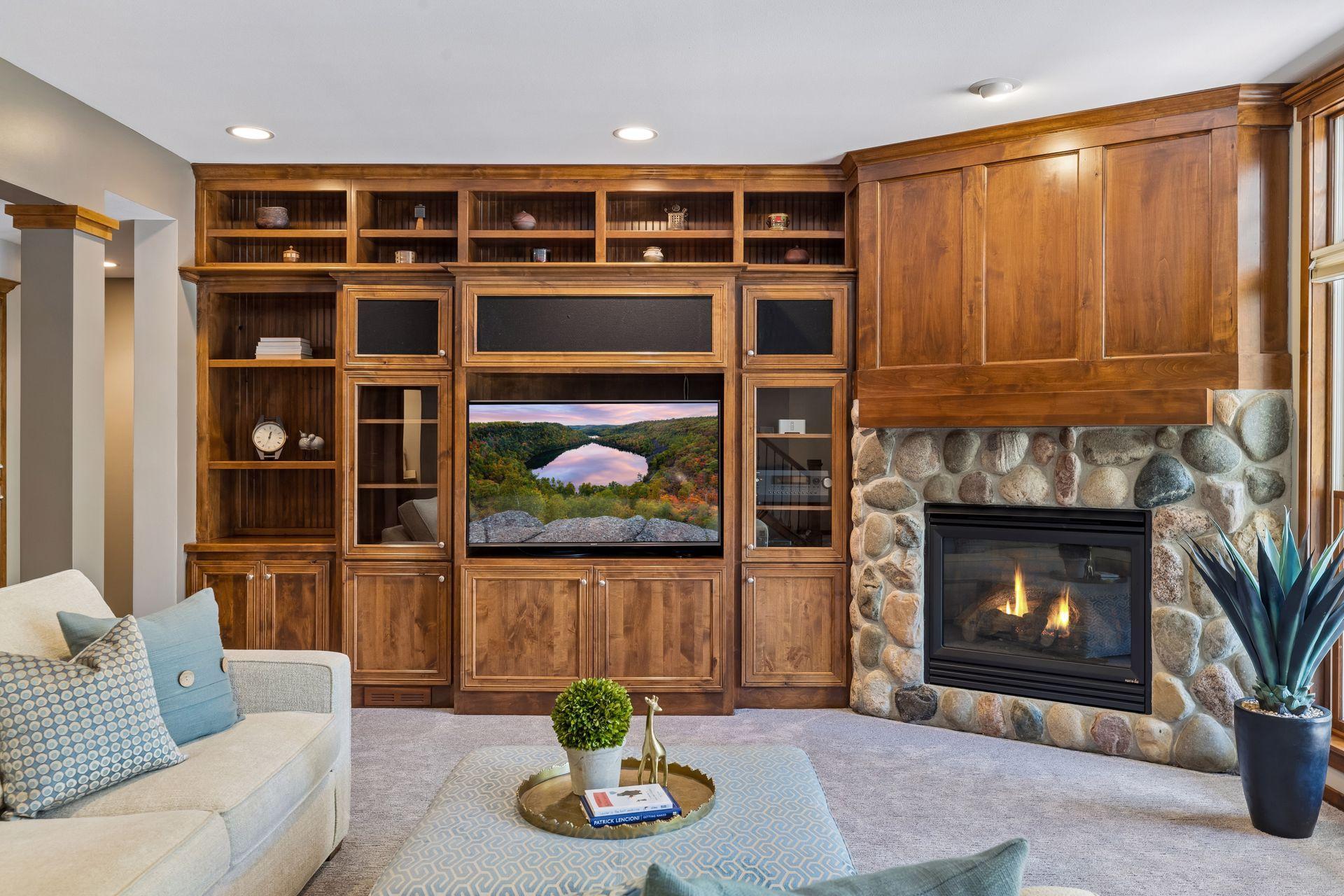 View of the beautiful alder wood, built-in entertainment center & stone gas fireplace. The lower level was freshly painted in 2026, and the carpet is newer (2021). The floors in the lower level are heated with a Munchkin high-efficiency heater.