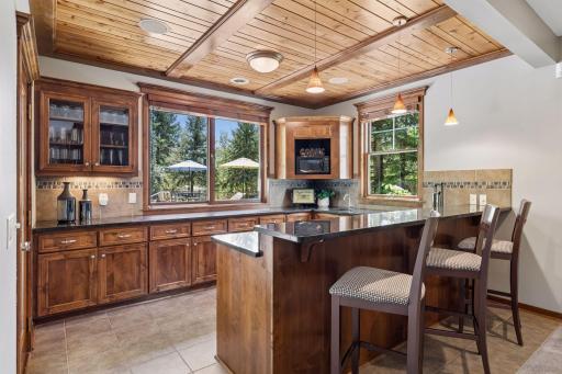 The lower-level walkout is beautifully crafted for entertaining. The built-in wet bar features a large pass-through window to the backyard Dekton counter, allowing seamless serving inside or out. Also includes cedar ceiling & ceramic tile floors.