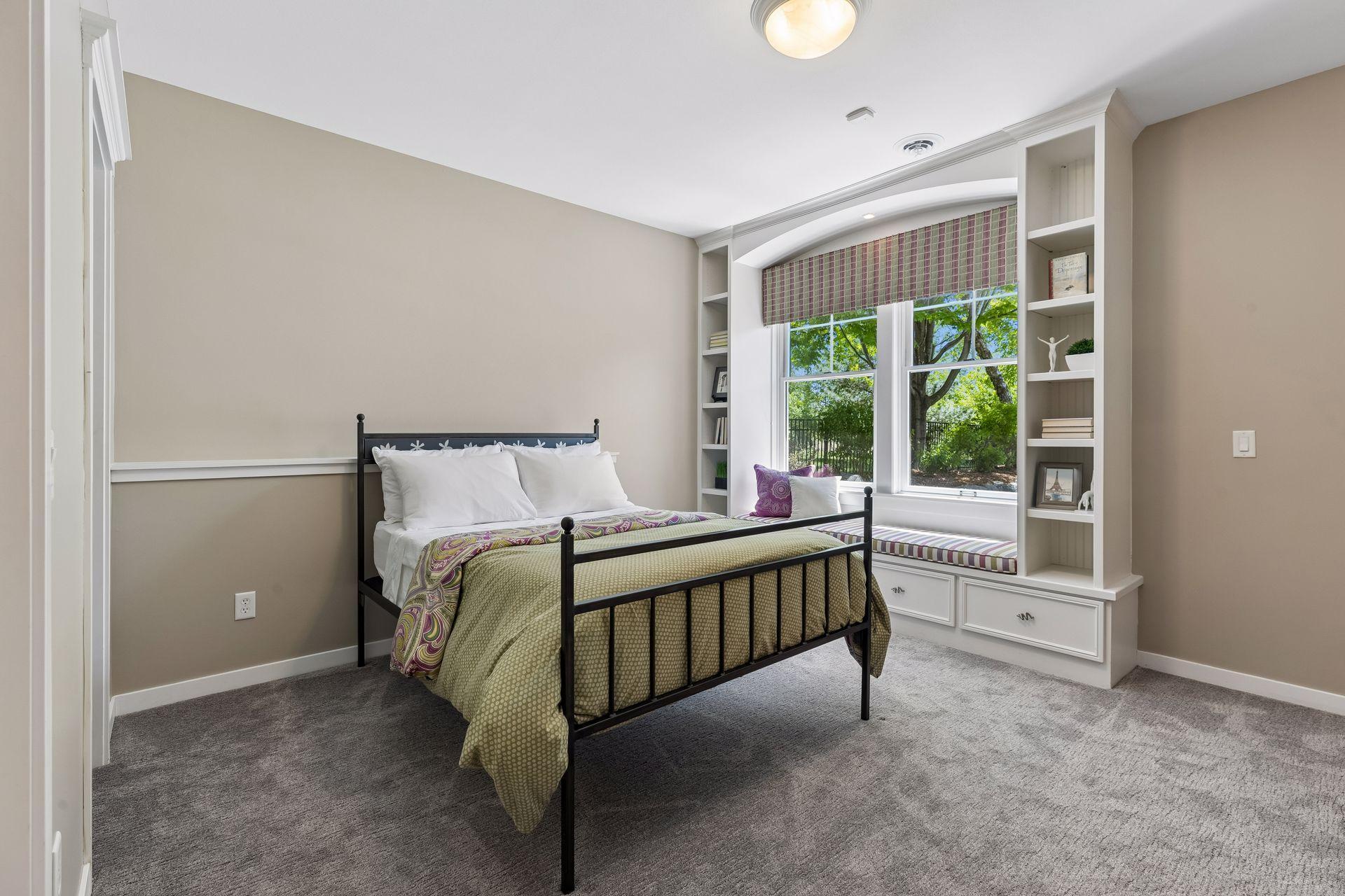 Bedroom 3 in the lower-level includes a custom-built-in window seat with bookshelves and storage. It overlooks the gorgeous backyard oasis.