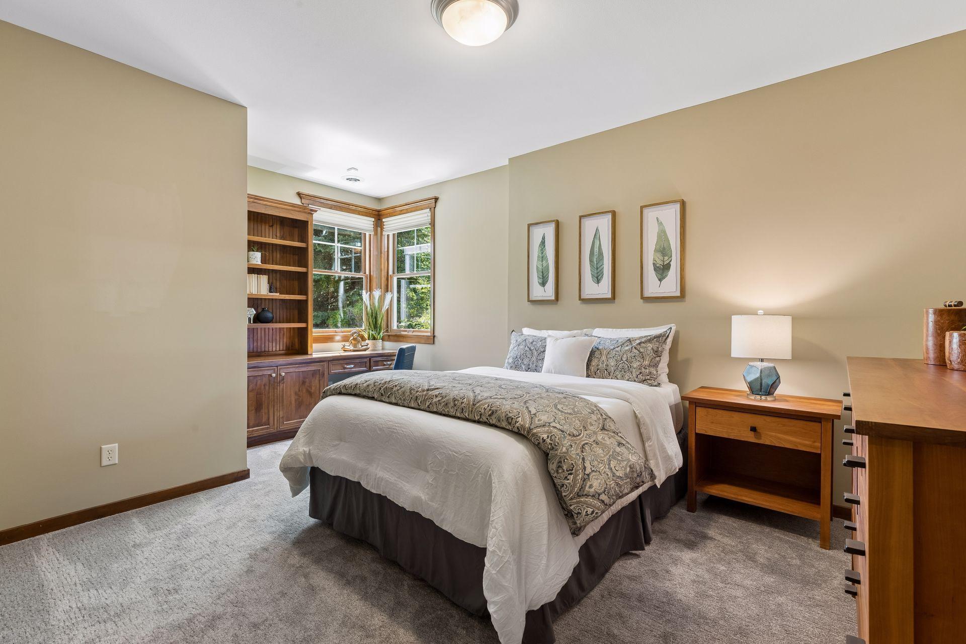 Bedroom 2 on the lower level features large corner windows that fill the room with natural light. It includes a built-in corner desk w/bookshelves & storage & a large closet with an organizational system.