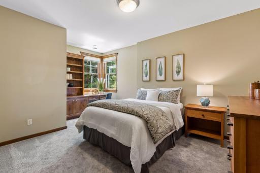 Bedroom 2 on the lower level features large corner windows that fill the room with natural light. It includes a built-in corner desk w/bookshelves & storage & a large closet with an organizational system.