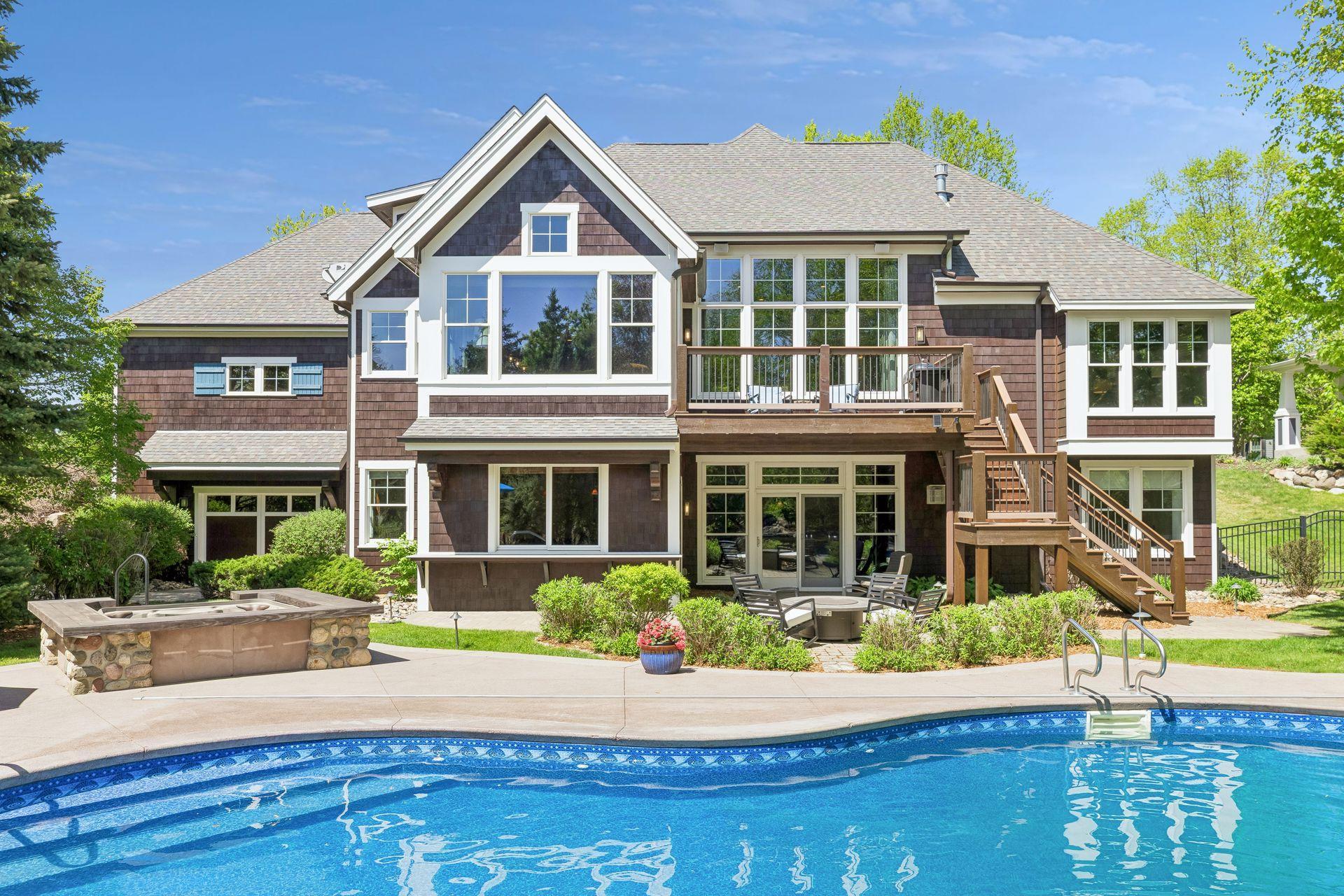 This view highlights the layout of the pool, TimberTech deck (2025), paver patio, hot tub & the large pass-through window to the inside bar w/a Dekton countertop for stools. Perfect for pool days.