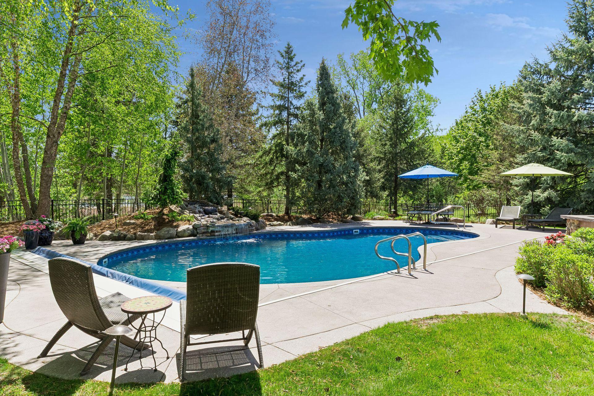 This view of the backyard highlights the pool, waterfall feature & the mature trees. There is a walking path beyond the property line & backs up to Fish Lake & wetlands.