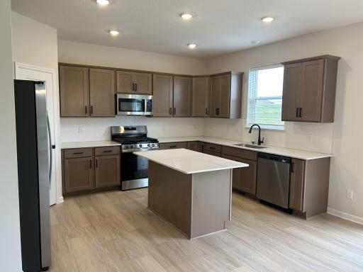 Kitchen includes walk-in pantry, stainless steel appliances and quartz countertops.