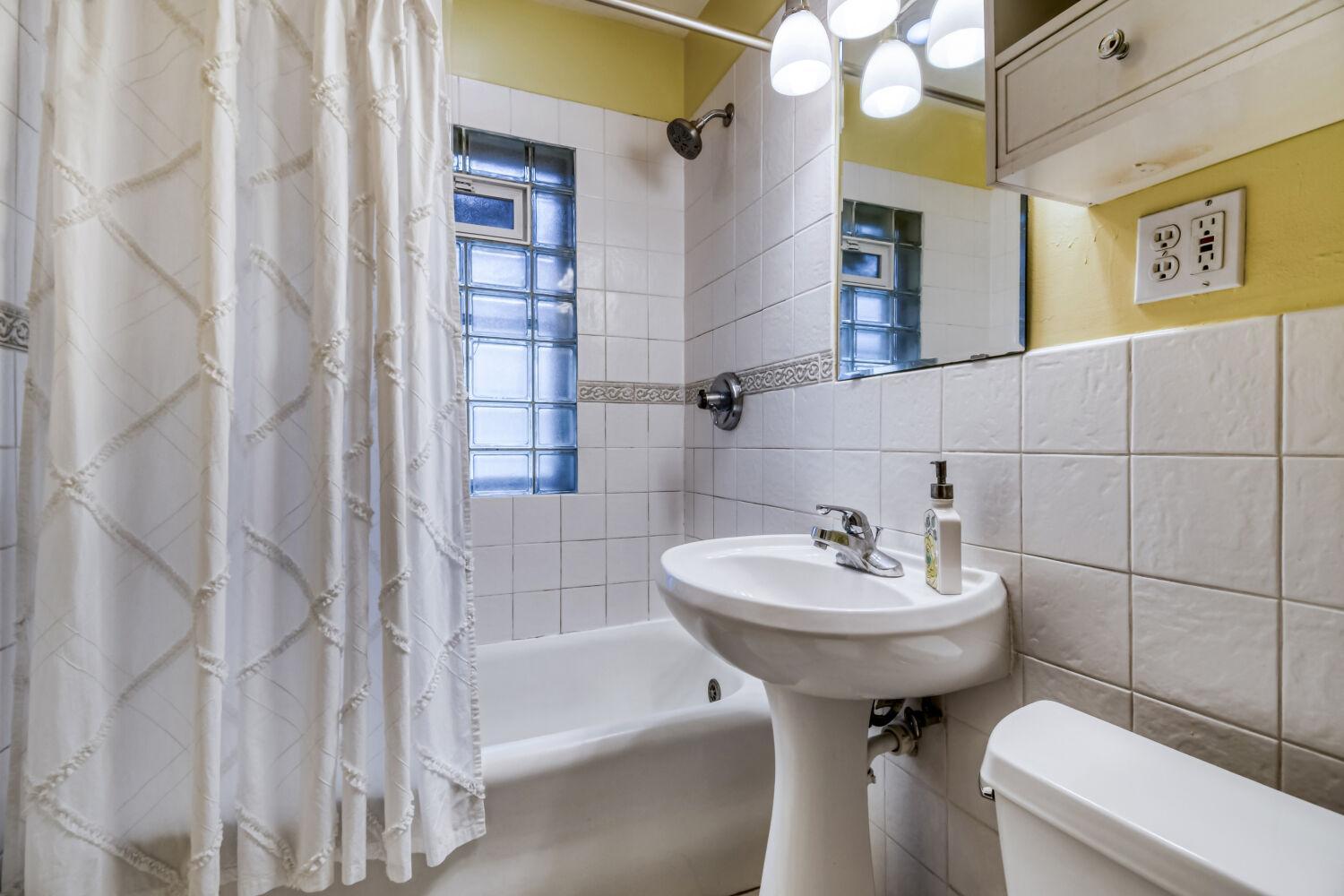 Full bath with tile surround and glass block window