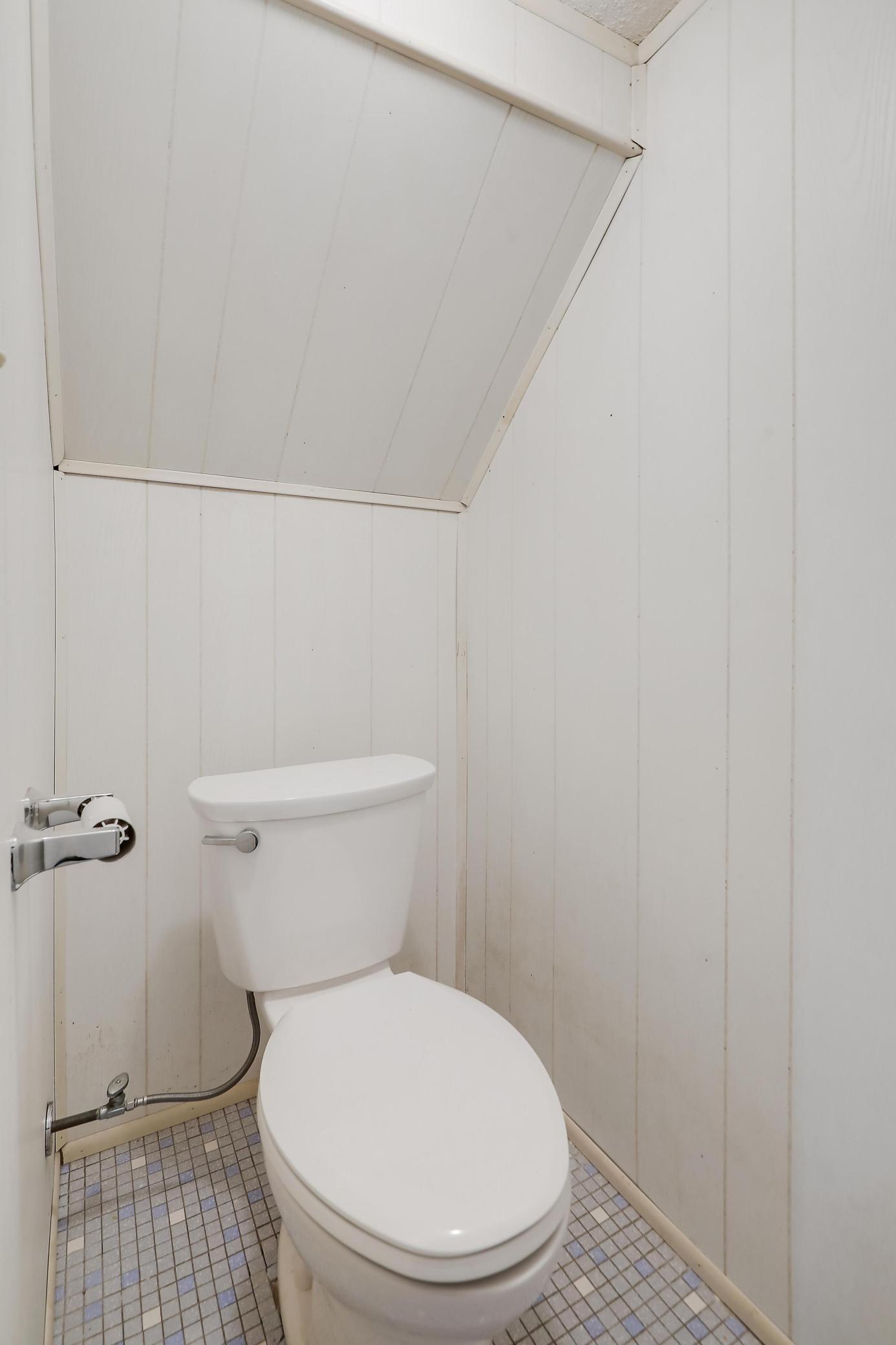 Cute one fourth bath includes white paneled walls.