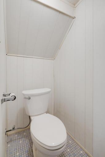 Cute one fourth bath includes white paneled walls.