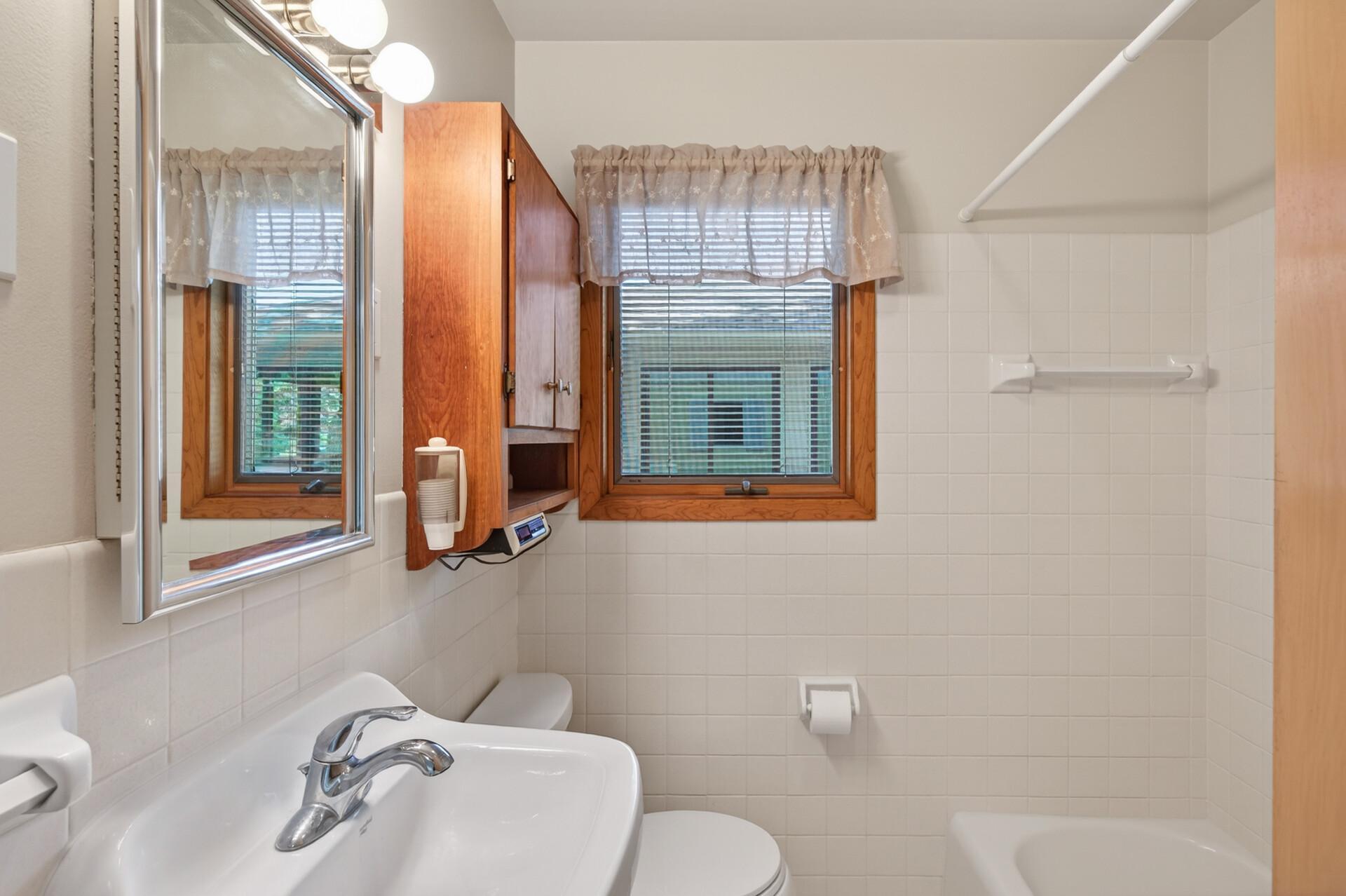 The main level full bath has a single casement window, ceramic tile tub surround and a ceramic tile wainscoting on the walls for easy care and cleaning..