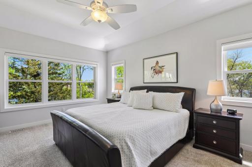 The main floor primary bedroom features large windows that face east and have private views of nature. The smaller windows facing south look at a large pond.