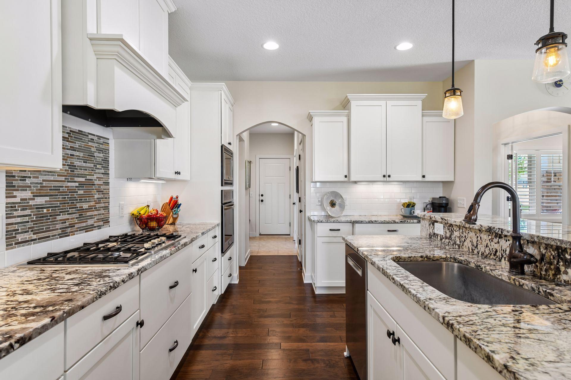 The archway and door lead to a guest bathroom, good size pantry, large storage closet, mud room and the attached 2-stall garage.