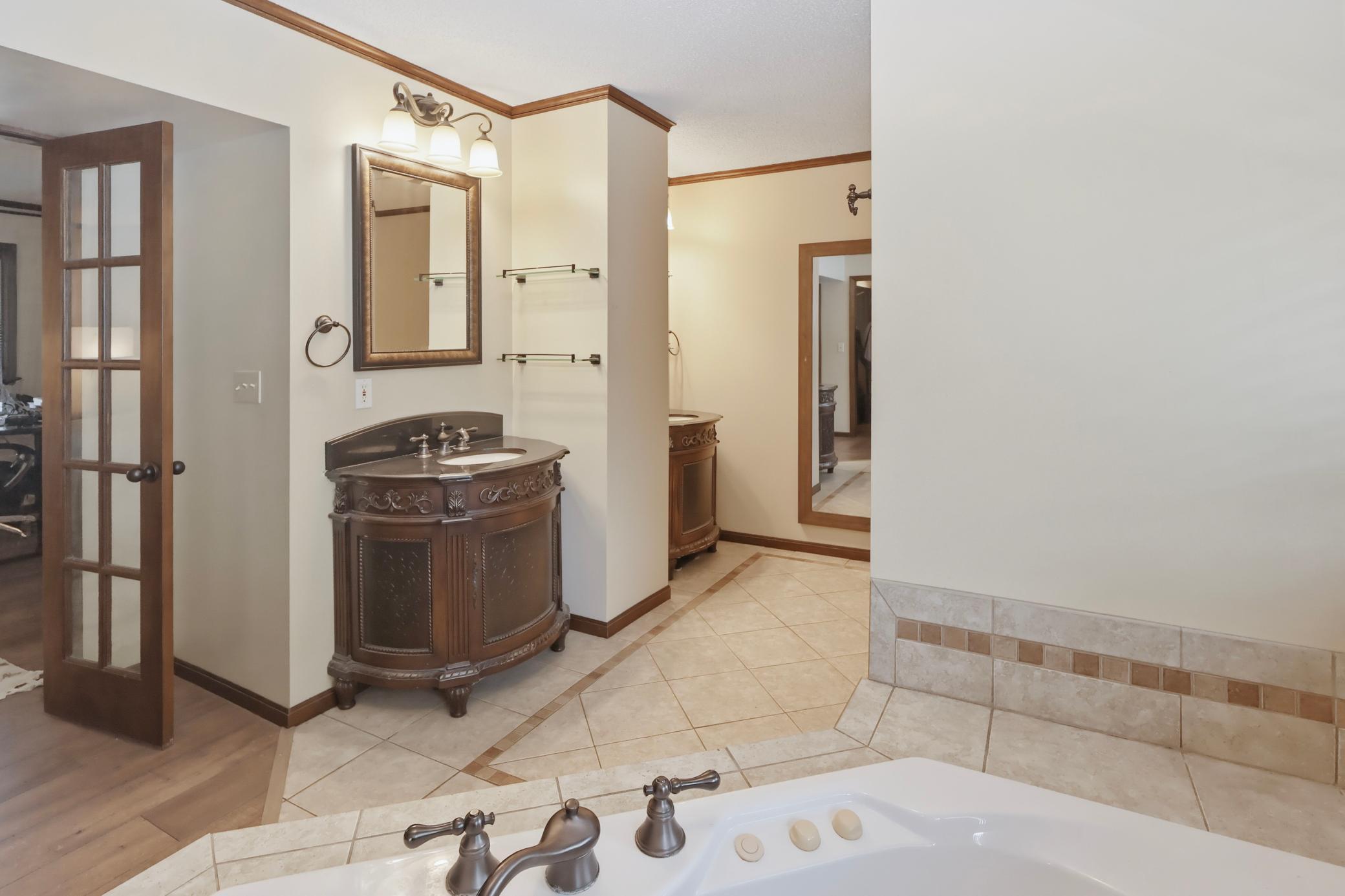 Double sinks, jet tub, and walk-in tile shower in the primary bathroom.