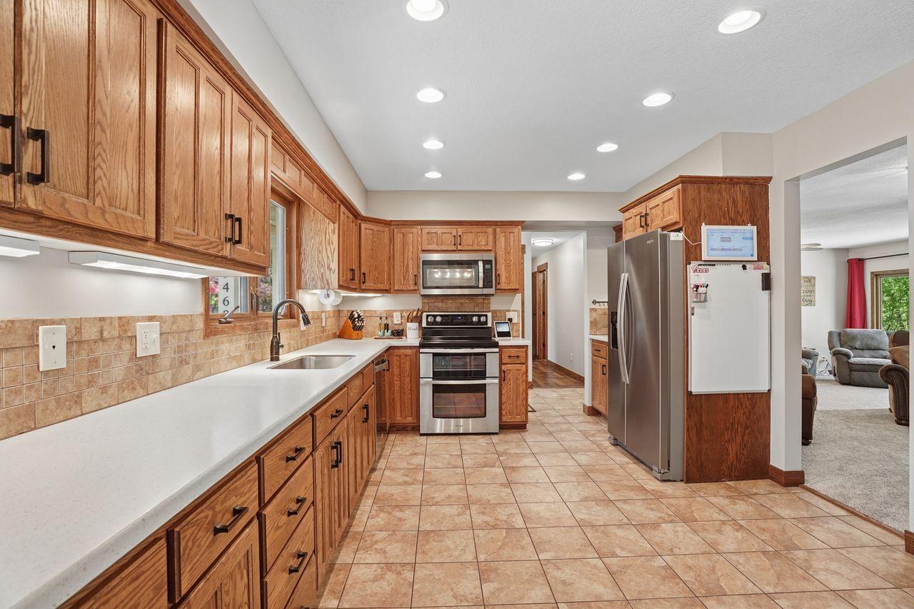 The updated modern, country-style kitchen includes a plethora of hardwood cabinetry, spacious Corian countertops, tile backsplash, bright recessed lighting and stainless steel appliances.