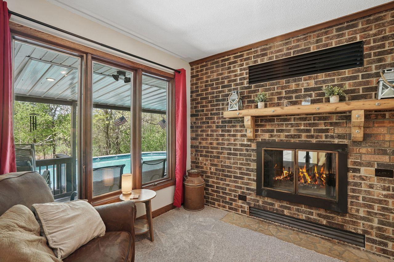 Gorgeous brick surround fireplace, with a nice wood mantle. Fire is for staging purposes only. Breathtaking views of the heavily wooded lot and sparkling pool.
