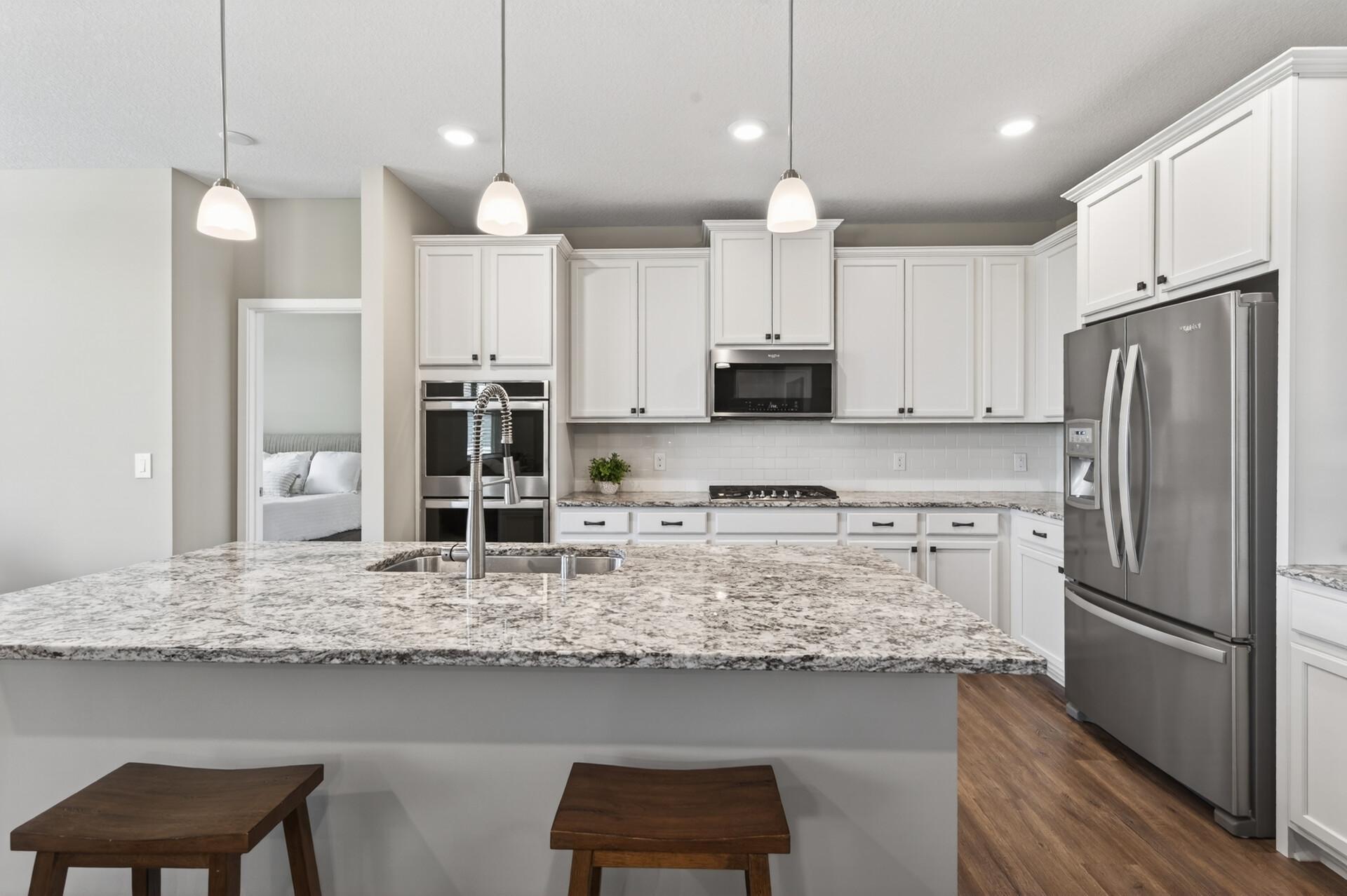 Dream chef kitchen with gas range, double ovens and tons of beautiful granite, countertop space. Plus staggered white kitchen cabinets with door pulls and handles.