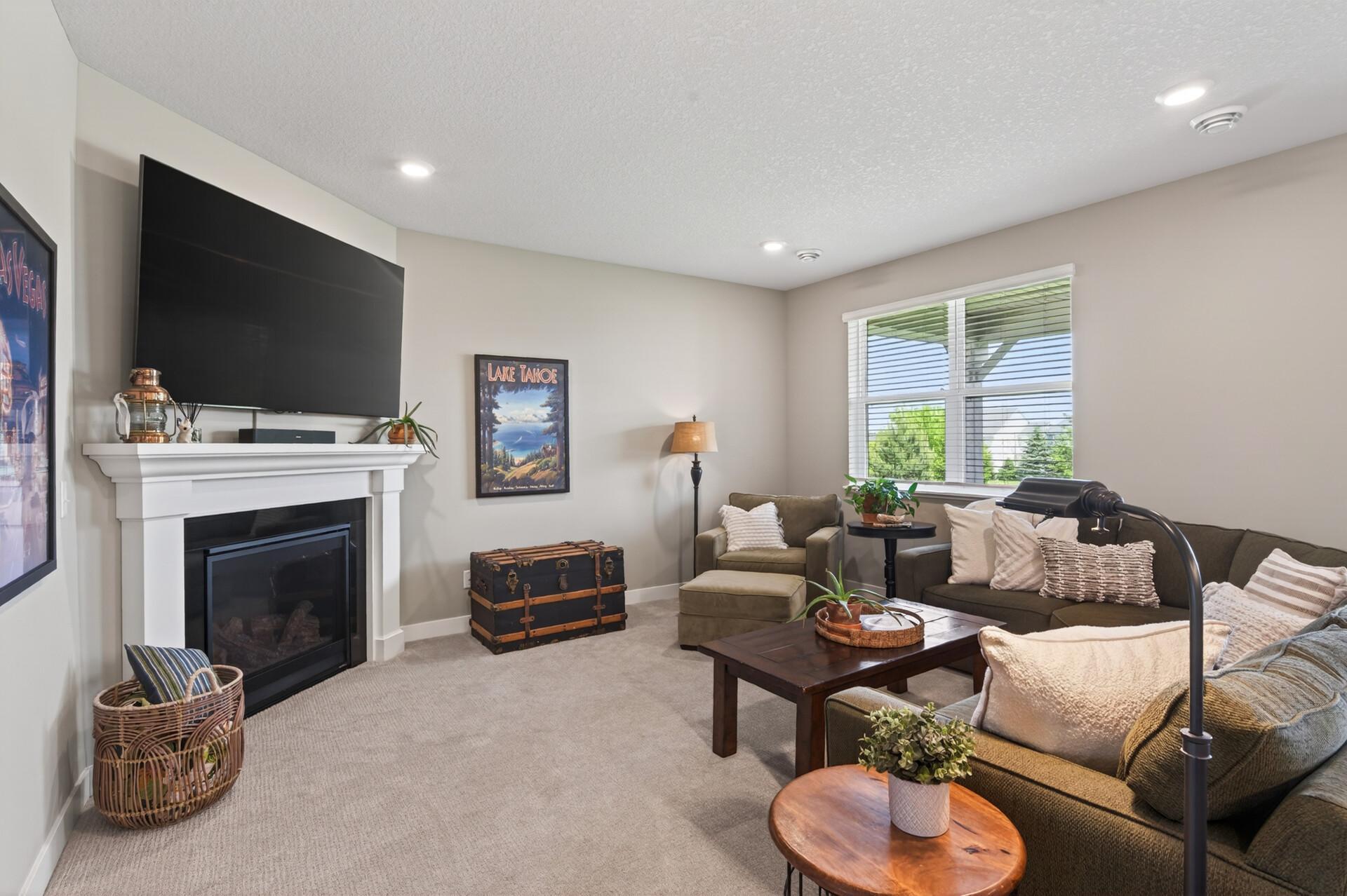 Spacious living room with corner gas fireplace with brick surround and wood mantle.
