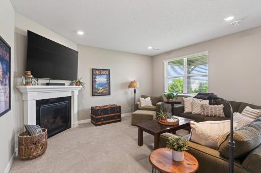 Spacious living room with corner gas fireplace with wood surround and mantle. Recessed lighting keeps this room light and bright.