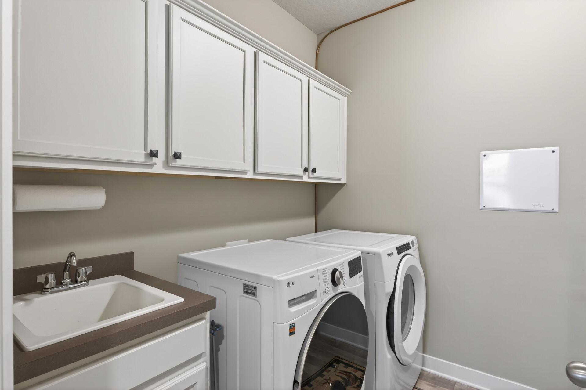 Steps away from the primary suite is this separate laundry room with sink, newer washer, dryer, and upper cabinetry. Also, your mechanical room with Air-to-Air exchanger, water softener and humidifier.