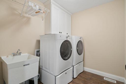 Convenient upper-level laundry room with storage and a utility sink.