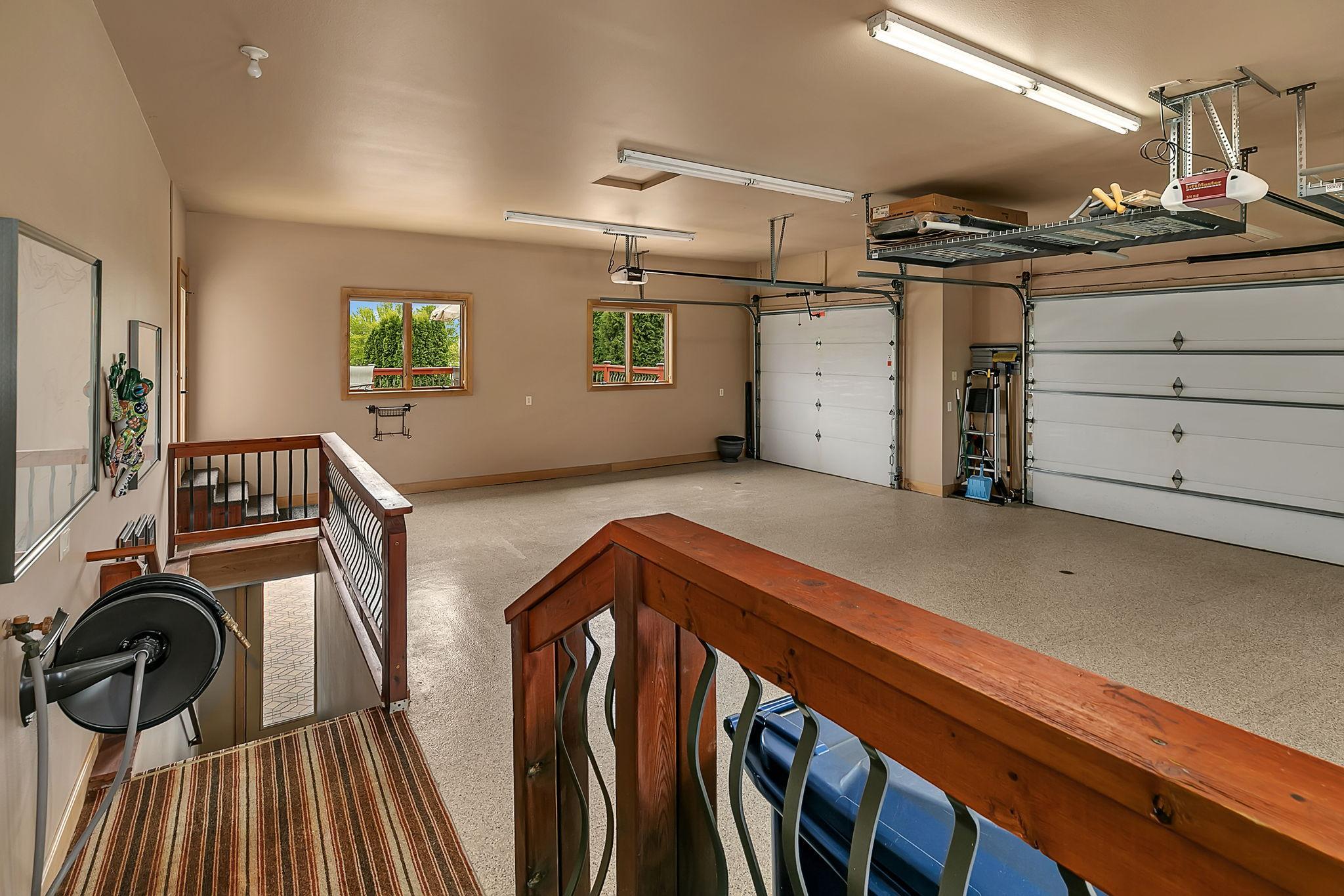 Functional stair access from the garage seamlessly connects to lower-level living spaces. Garage has floor drains with drainable catch basins below. Stairs shown here also access the lower level garage space.