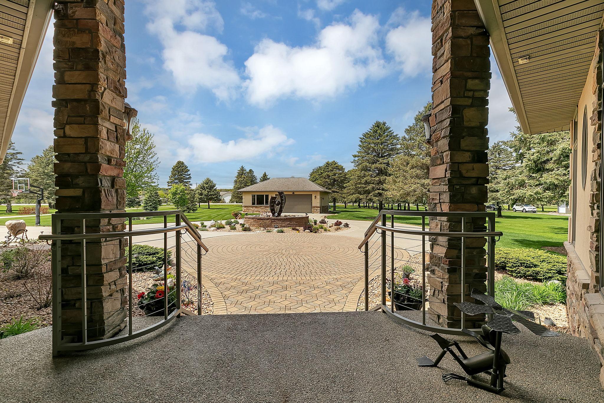 Covered front porch shelters you from outdoor elements as you wait to step inside. Metal railings are a great design item that compliments the stone and numerous scuptures.