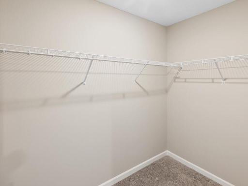 Primary Walk In Closet. Photo taken of another home with similar plan and finishes. Photos and renderings may not depict actual plan, materials, & finishes may vary. All measurements are approximate.