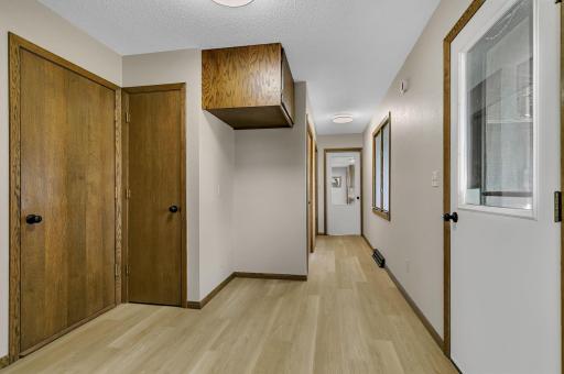 Hallway connects owners suite and laundry to main living and kitchen. Door to the right seen here lends back yard and deck access. Door to the left is another garage access from this wing.