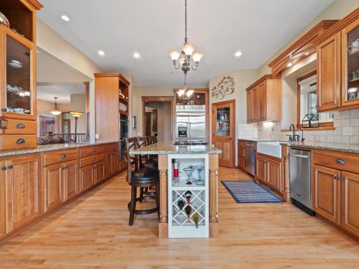 The kitchen is lit by classic chandeliers and natural light streaming in from large windows.