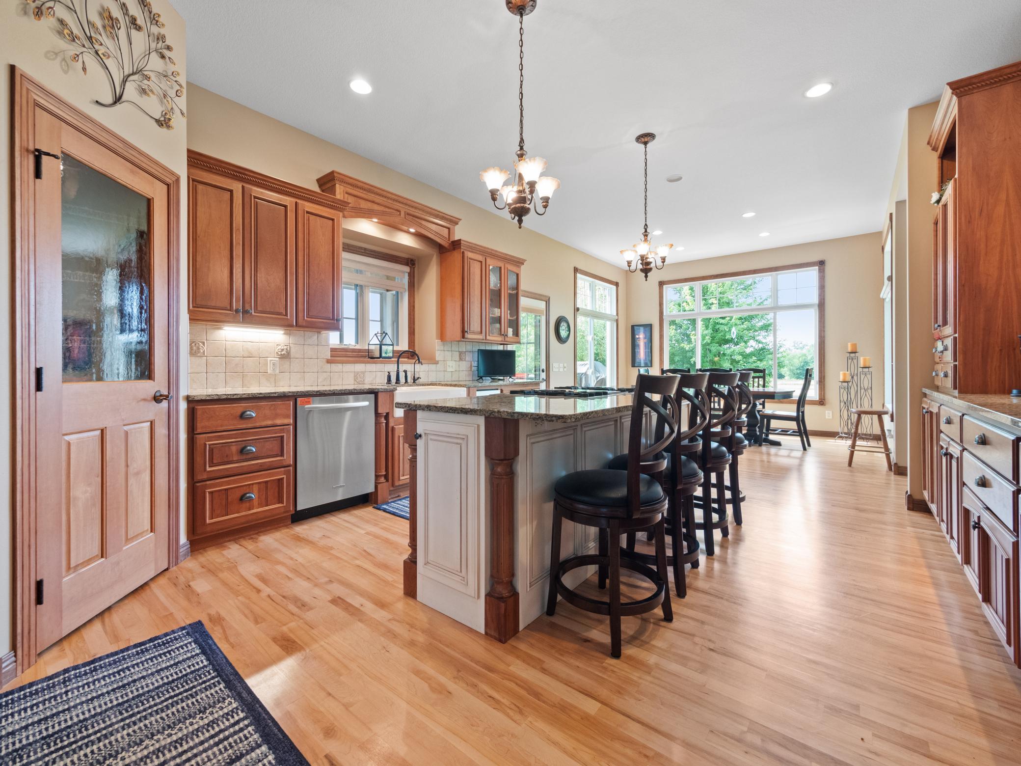 A spacious and warm kitchen features wooden cabinetry, sleek countertops and a large kitchen island with seating.