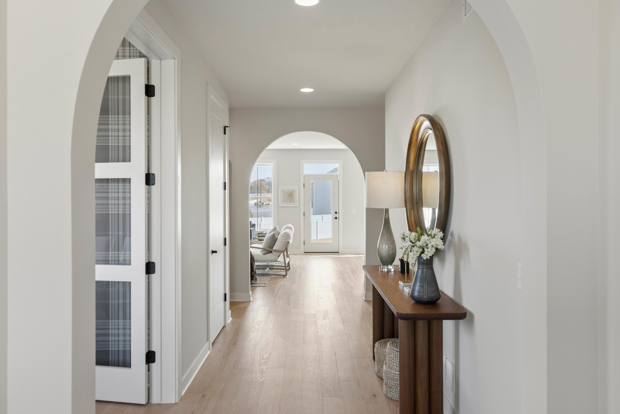 Foyer features graceful arched openings and wide-planked oak floors.