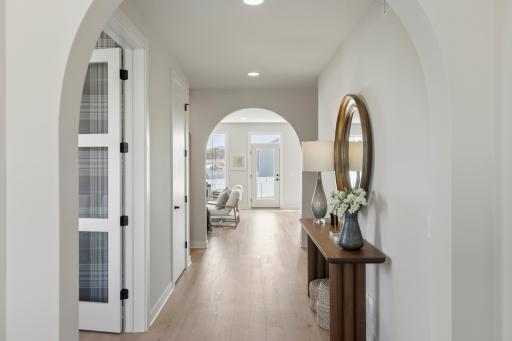 Foyer features graceful arched openings and wide-planked oak floors.