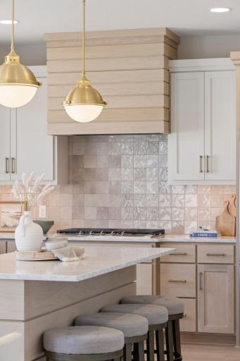 Kitchen features white oak plank range hood and center island.