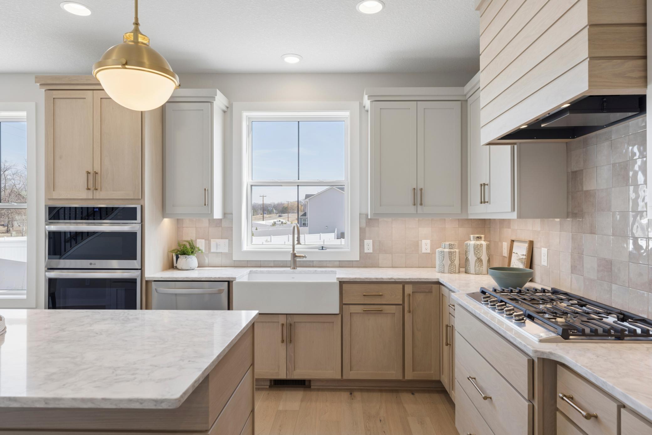 Gas cooktop with vented hood and ceramic tile backsplash.