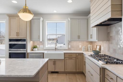 Gas cooktop with vented hood and ceramic tile backsplash.