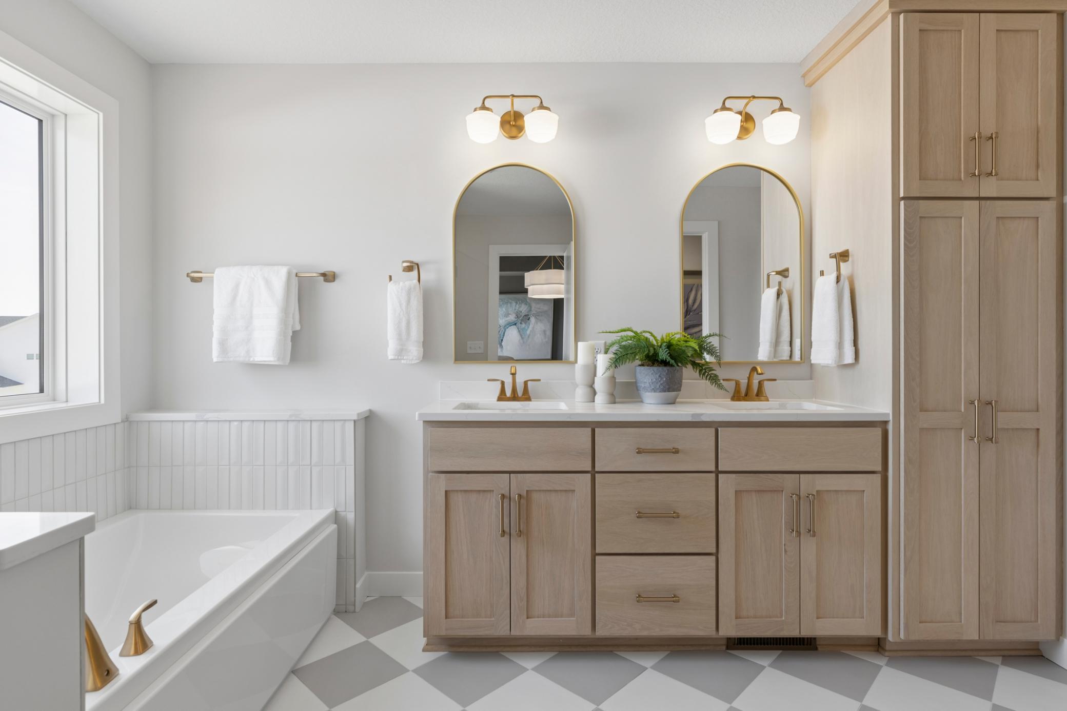 Primary bath features double sink vanity with quartz countertops and linen cabinet.