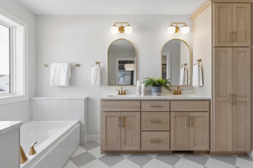 Primary bath features double sink vanity with quartz countertops and linen cabinet.