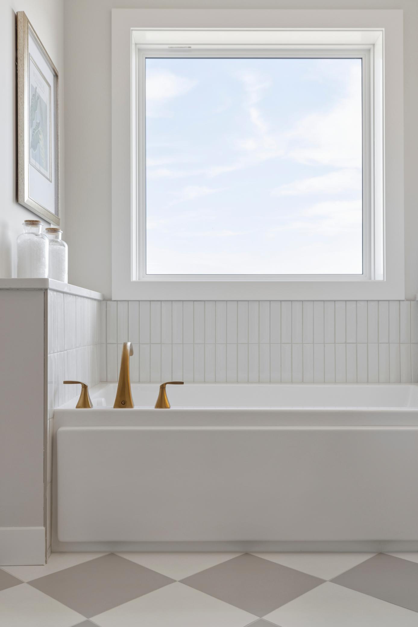 Tub with large window and beautiful tile backsplash in primary bath.