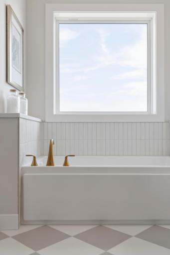 Tub with large window and beautiful tile backsplash in primary bath.
